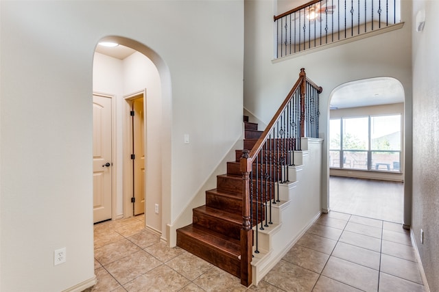 staircase featuring a towering ceiling and tile patterned flooring