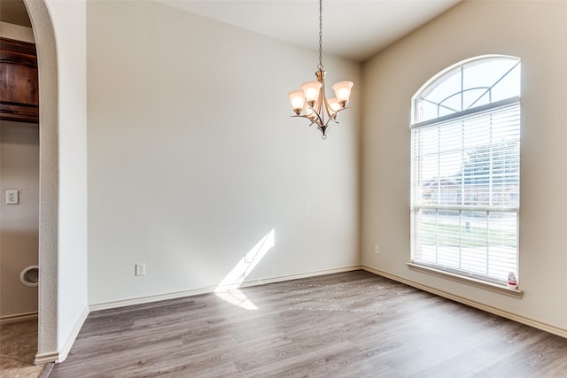 spare room with a notable chandelier and hardwood / wood-style flooring