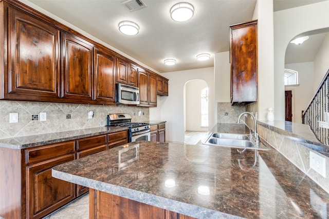 kitchen featuring tasteful backsplash, appliances with stainless steel finishes, sink, and kitchen peninsula