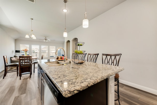 kitchen featuring ceiling fan with notable chandelier, a kitchen island with sink, sink, dishwasher, and light hardwood / wood-style floors