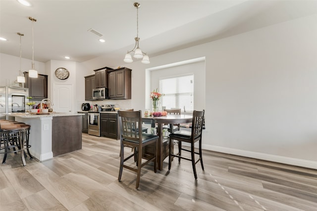 dining space featuring light hardwood / wood-style flooring and a notable chandelier