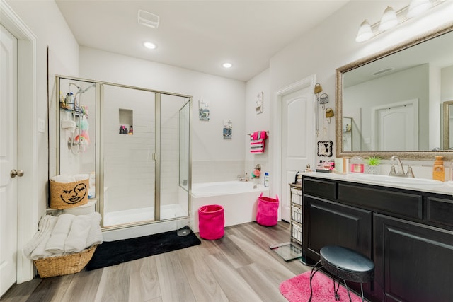 bathroom with plus walk in shower, hardwood / wood-style floors, and vanity