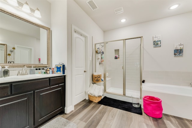 bathroom with wood-type flooring, vanity, and shower with separate bathtub