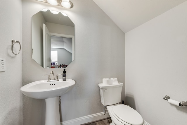 bathroom with hardwood / wood-style floors, toilet, and lofted ceiling