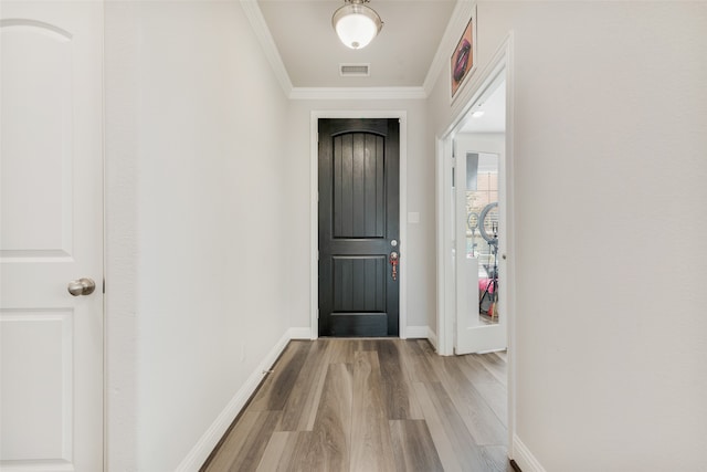 entryway with ornamental molding and light wood-type flooring