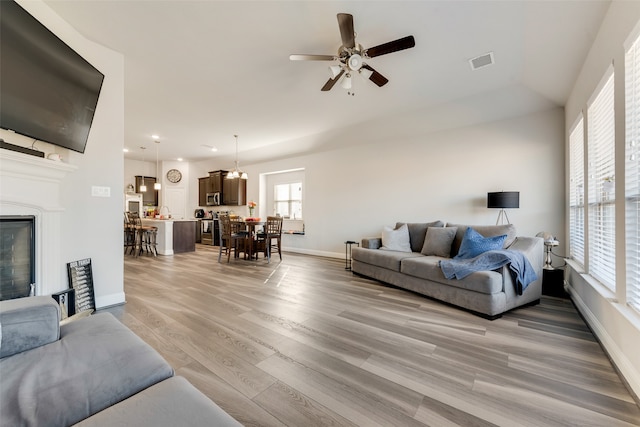 living room with light wood-type flooring, vaulted ceiling, and ceiling fan