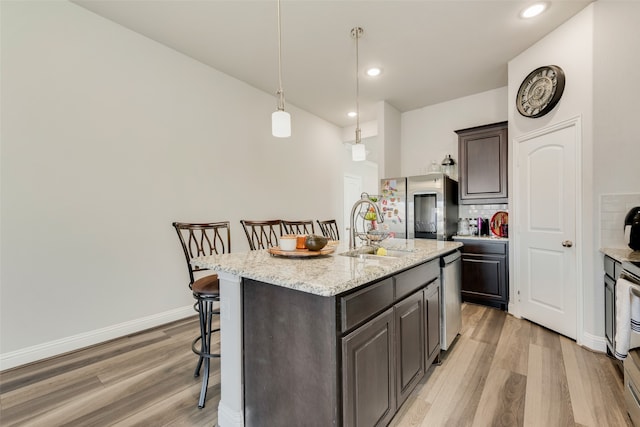 kitchen with a breakfast bar, an island with sink, light wood-type flooring, and sink