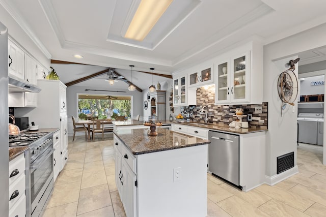 kitchen with a kitchen island, appliances with stainless steel finishes, white cabinetry, dark stone countertops, and pendant lighting