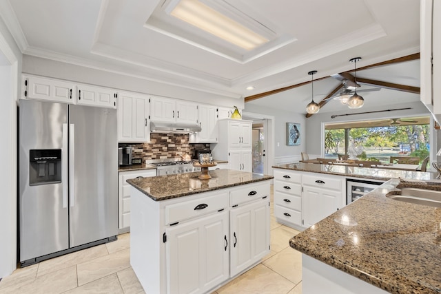 kitchen featuring stainless steel fridge, white cabinetry, a kitchen island, and dark stone countertops