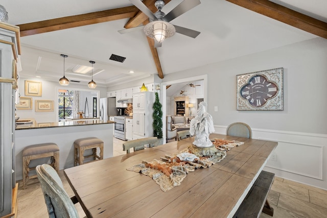 dining space with ornamental molding, beam ceiling, and ceiling fan