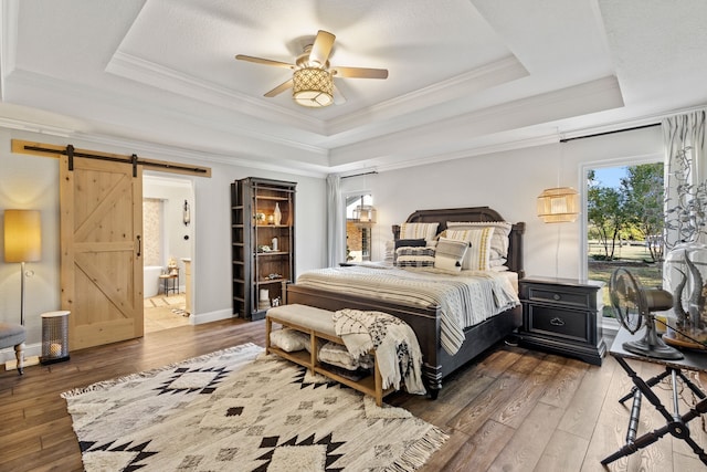 bedroom with dark wood-type flooring, ceiling fan, a raised ceiling, and a barn door