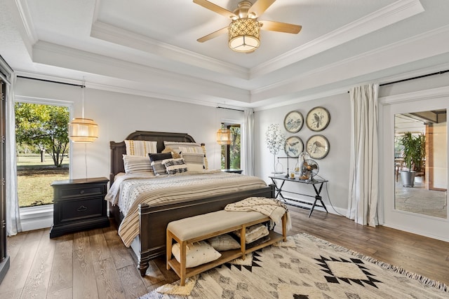 bedroom with ceiling fan, hardwood / wood-style flooring, ornamental molding, and a tray ceiling