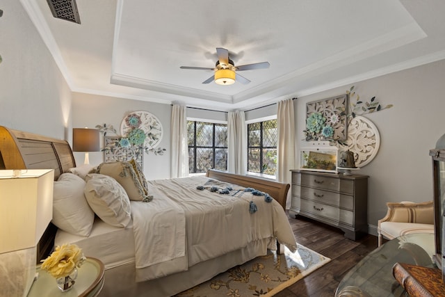 bedroom featuring ceiling fan, ornamental molding, a tray ceiling, and dark hardwood / wood-style floors