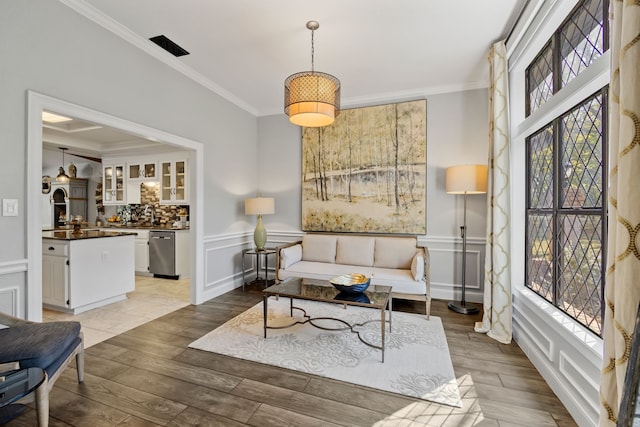 sitting room with crown molding and light hardwood / wood-style flooring