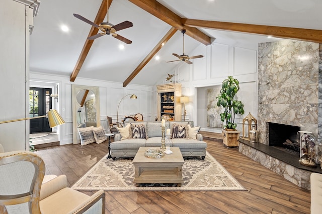 living room featuring a premium fireplace, lofted ceiling with beams, wood-type flooring, and ceiling fan