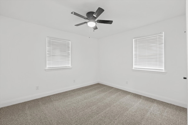 carpeted spare room featuring a wealth of natural light and ceiling fan