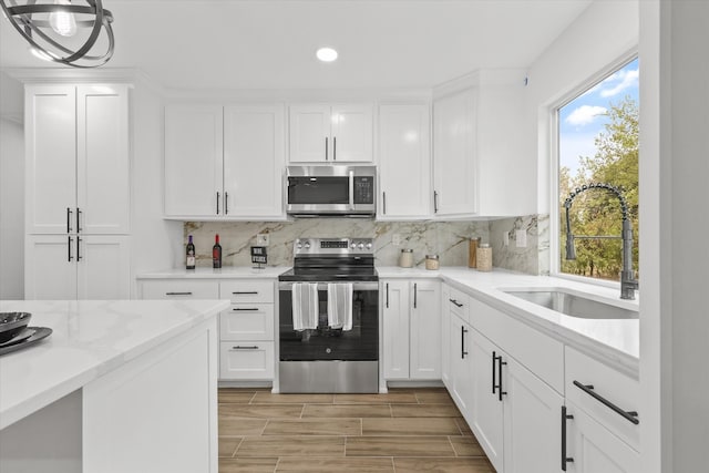 kitchen with white cabinetry, a wealth of natural light, sink, and appliances with stainless steel finishes