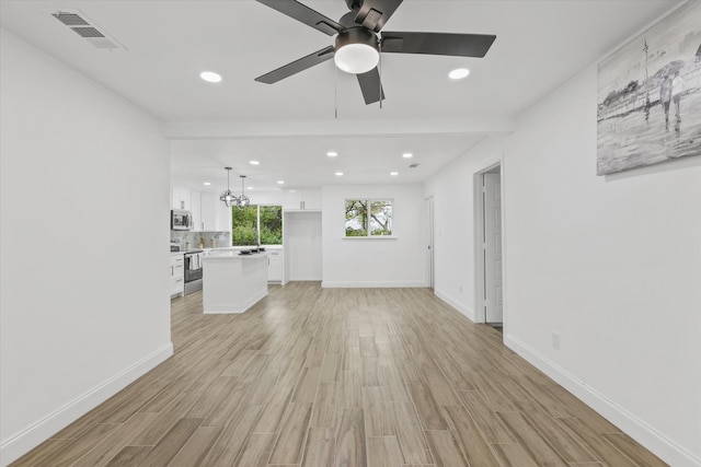 unfurnished living room with ceiling fan with notable chandelier and light wood-type flooring