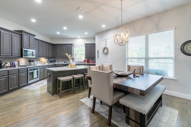 dining room featuring sink, a chandelier, and light wood-type flooring