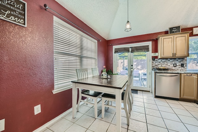 kitchen with tasteful backsplash, lofted ceiling, pendant lighting, stainless steel dishwasher, and light tile patterned floors