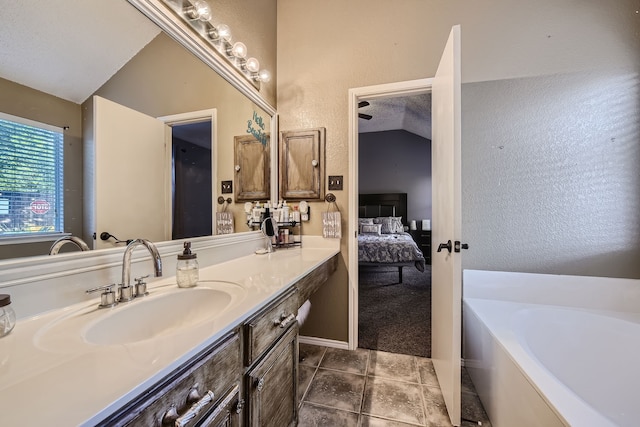 bathroom with a textured ceiling, lofted ceiling, vanity, a bathtub, and tile patterned flooring