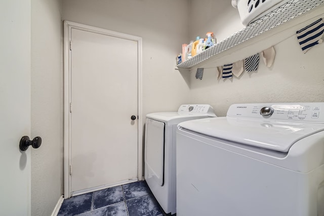 laundry area featuring washing machine and dryer and dark tile patterned flooring