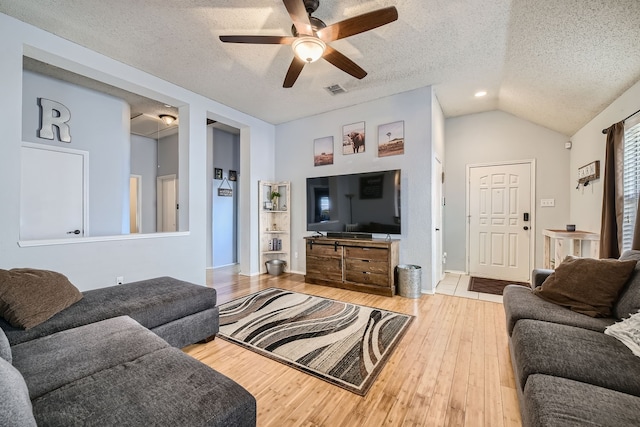 living room featuring a textured ceiling, hardwood / wood-style flooring, vaulted ceiling, and ceiling fan