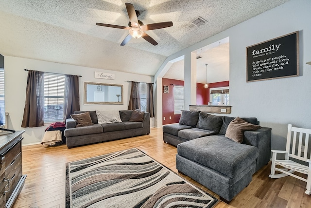 living room featuring hardwood / wood-style floors, ceiling fan, a textured ceiling, and vaulted ceiling