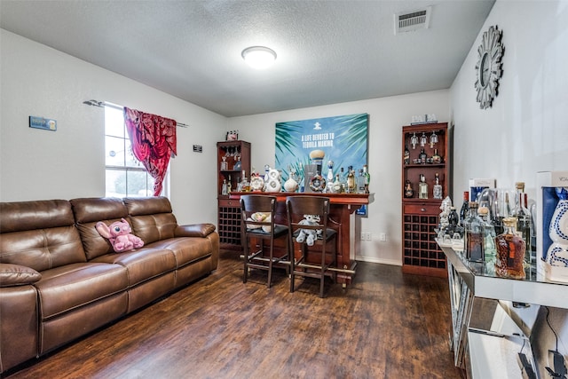 living room featuring a textured ceiling, indoor bar, and dark hardwood / wood-style flooring