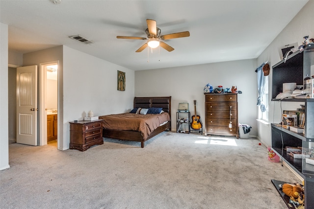 carpeted bedroom with ensuite bath and ceiling fan