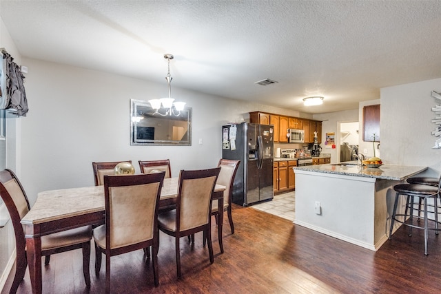 dining area featuring a chandelier, sink, a textured ceiling, and light wood-type flooring