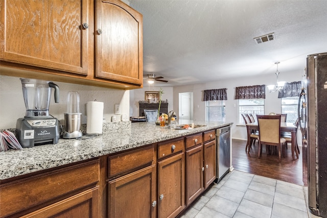 kitchen featuring light stone counters, sink, ceiling fan with notable chandelier, light hardwood / wood-style floors, and stainless steel appliances