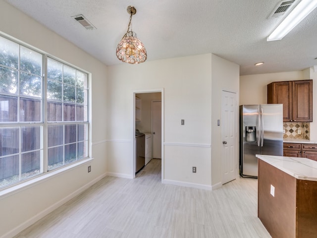 kitchen with tasteful backsplash, independent washer and dryer, stainless steel fridge, decorative light fixtures, and a notable chandelier