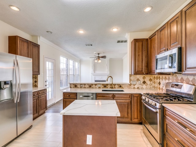 kitchen with sink, a center island, ceiling fan, stainless steel appliances, and ornamental molding