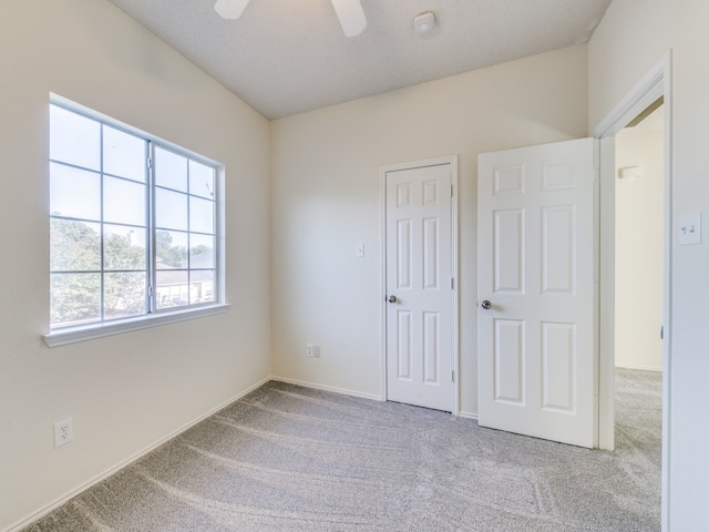 unfurnished bedroom with a closet, a textured ceiling, light colored carpet, and ceiling fan