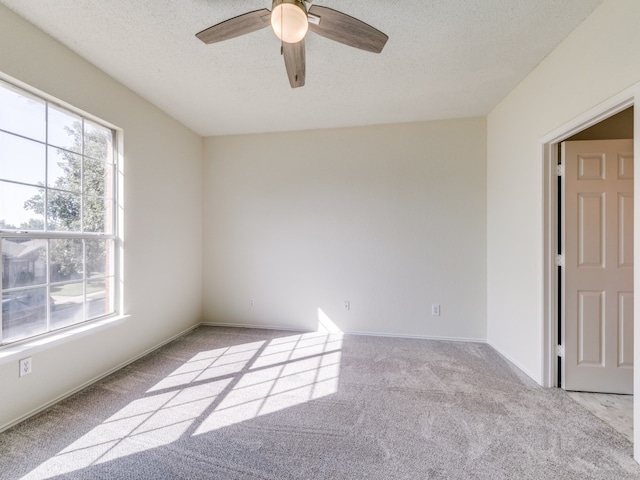 unfurnished room with a textured ceiling, light colored carpet, and ceiling fan