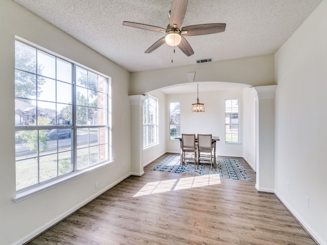 dining area featuring a textured ceiling, wood-type flooring, and ceiling fan with notable chandelier