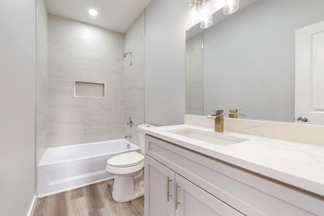 full bathroom with vanity, hardwood / wood-style floors, tiled shower / bath combo, and toilet