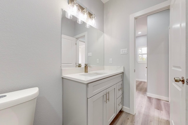 bathroom featuring toilet, hardwood / wood-style flooring, and vanity