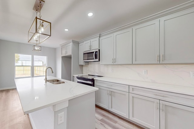 kitchen featuring light stone countertops, appliances with stainless steel finishes, sink, light hardwood / wood-style floors, and pendant lighting