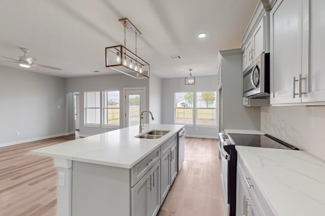 kitchen featuring a center island with sink, gray cabinets, sink, light hardwood / wood-style floors, and stainless steel appliances