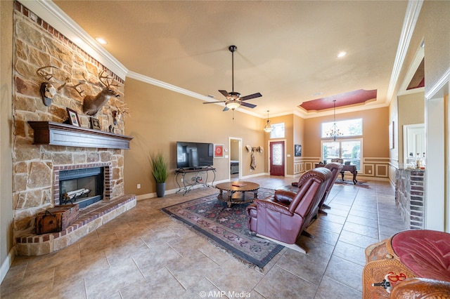 tiled living room with crown molding, ceiling fan with notable chandelier, and a fireplace