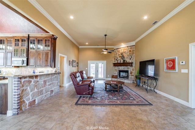 tiled living room with ornamental molding, french doors, a fireplace, and ceiling fan