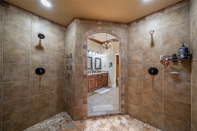 bathroom featuring vanity, ornamental molding, and tiled shower