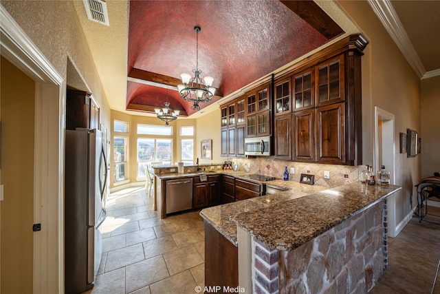 kitchen with backsplash, kitchen peninsula, hanging light fixtures, stainless steel appliances, and dark stone countertops