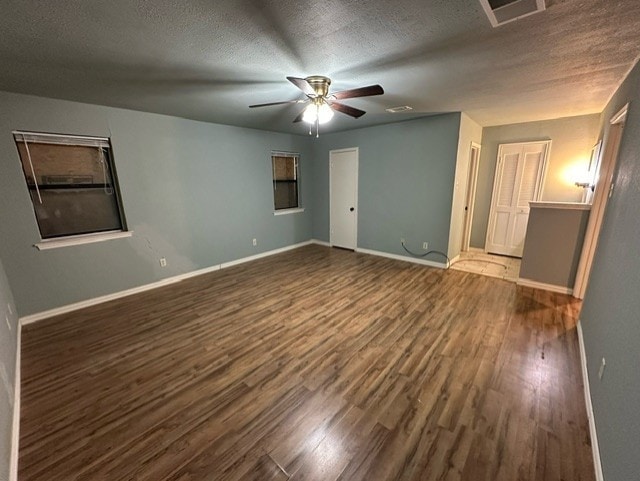 unfurnished room featuring ceiling fan, dark wood-type flooring, and a textured ceiling