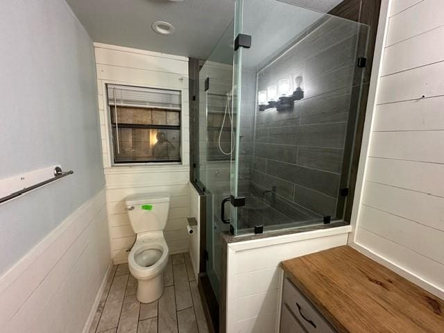 bathroom featuring a shower with shower door and toilet