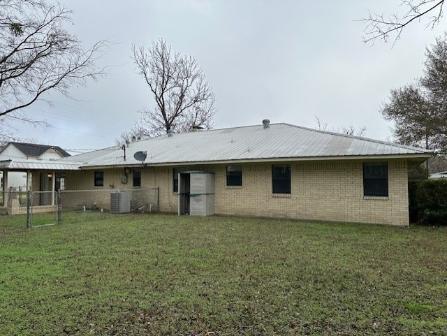 back of house with cooling unit and a lawn