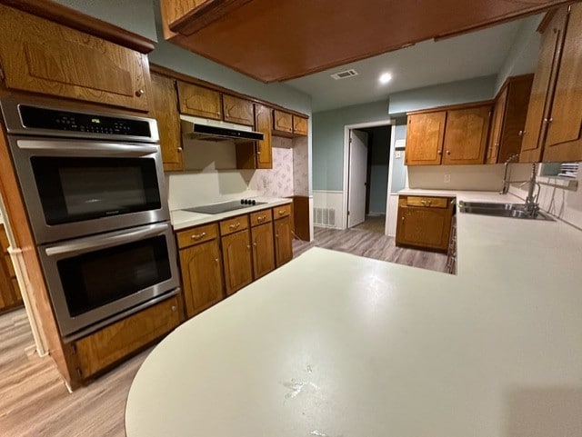 kitchen with sink, double oven, kitchen peninsula, black electric cooktop, and dishwashing machine