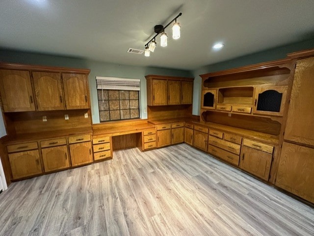 kitchen with built in desk, light hardwood / wood-style floors, and track lighting